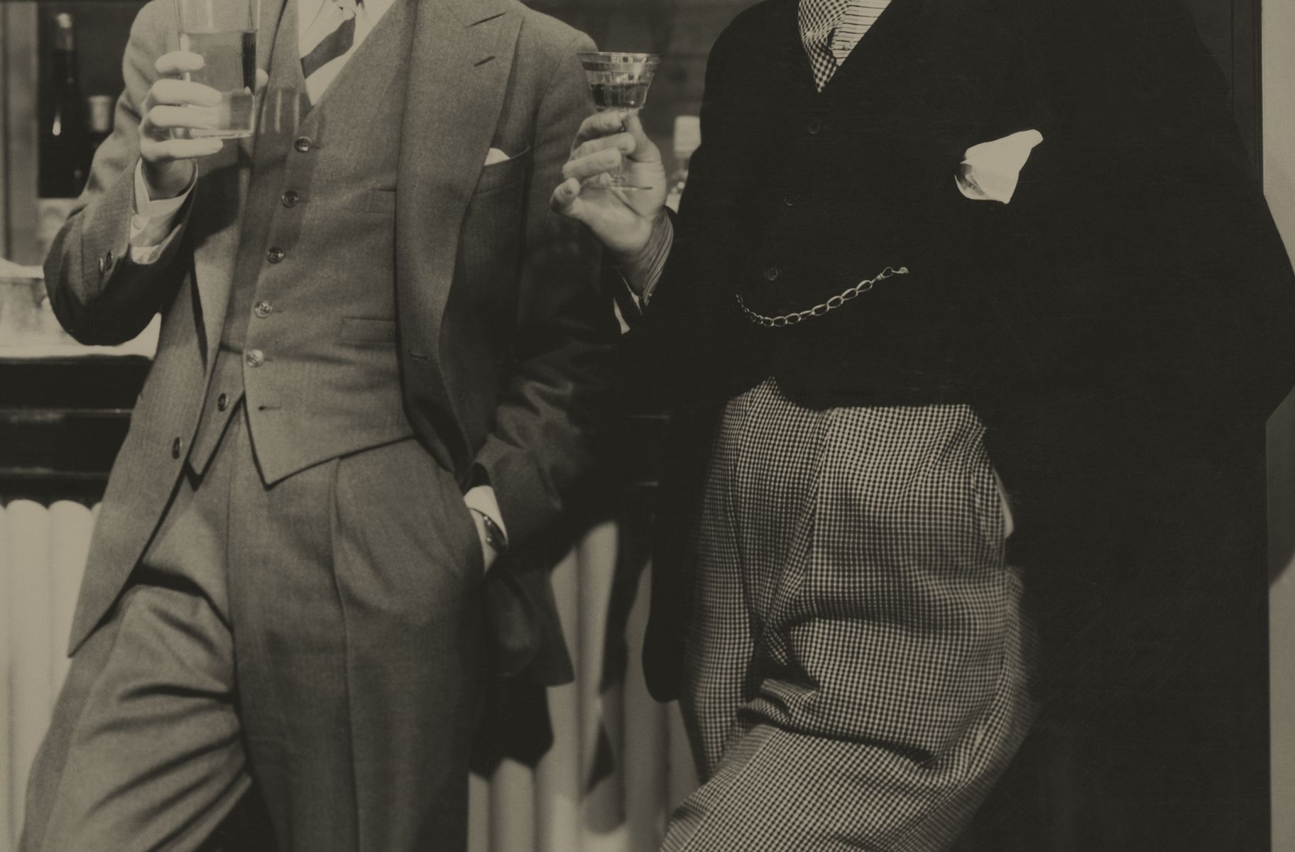 Two men in 1930s attire with drinks in hand 