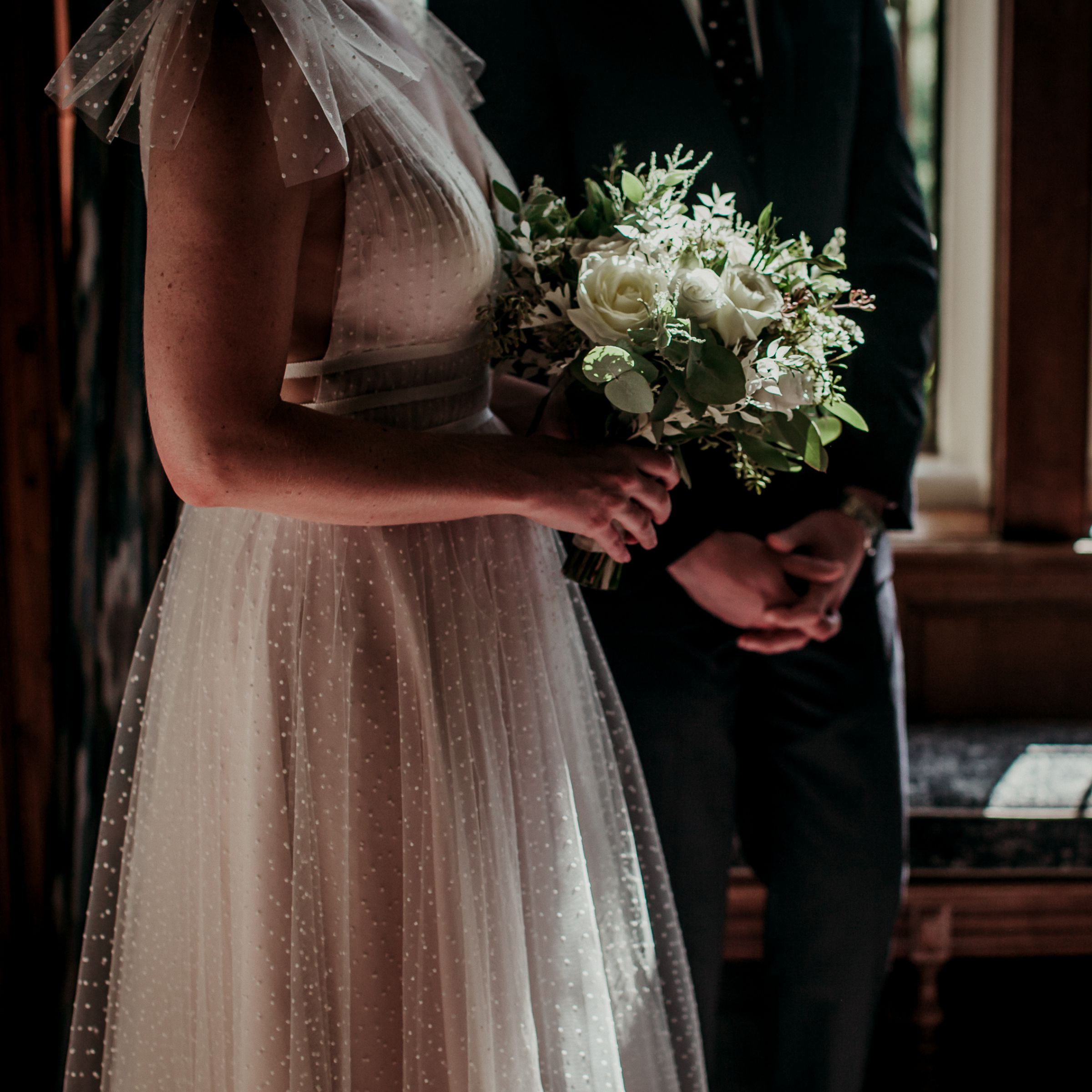 Body shot of married couple with flowers and attire 
