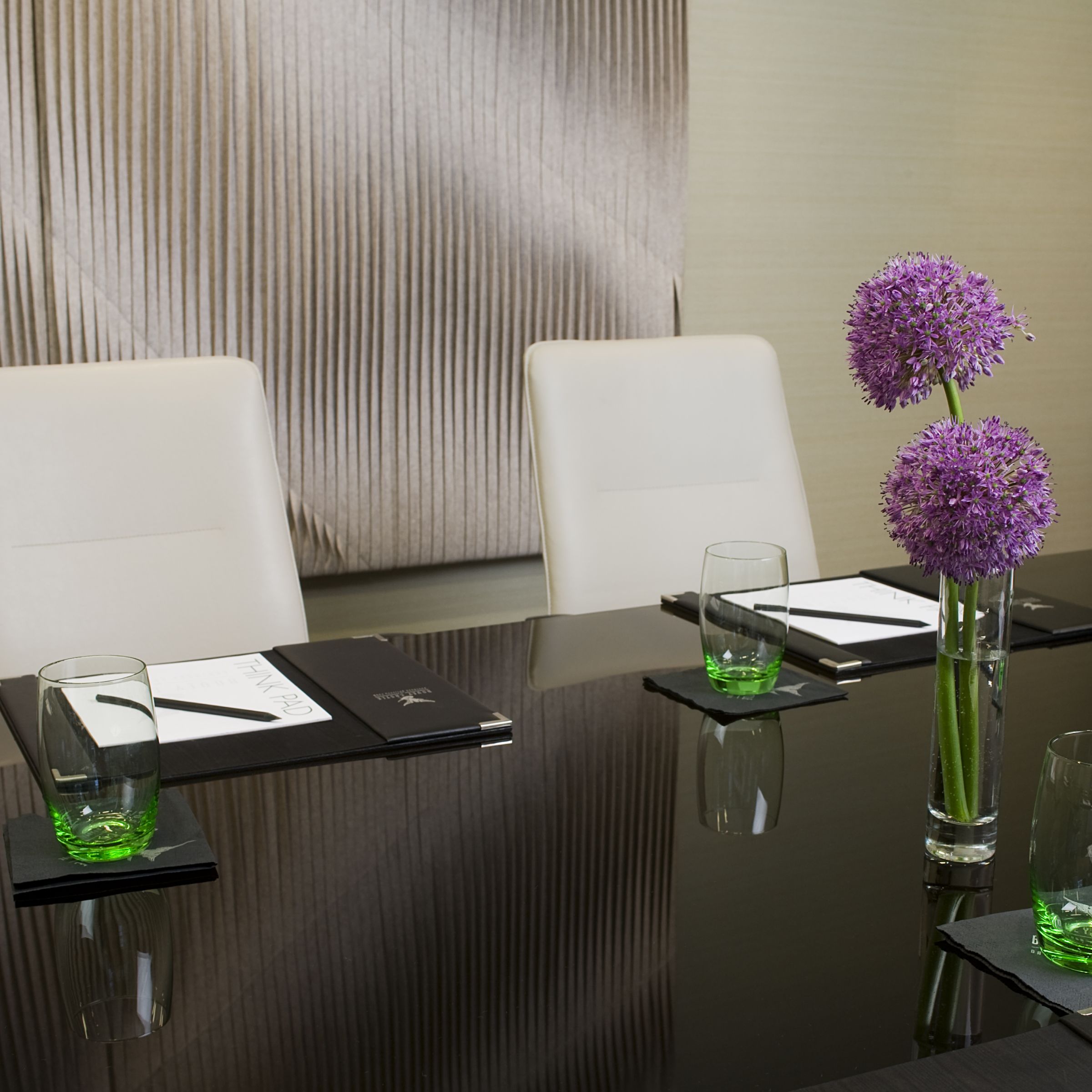 boardroom table with notepads, glasses and flowers 