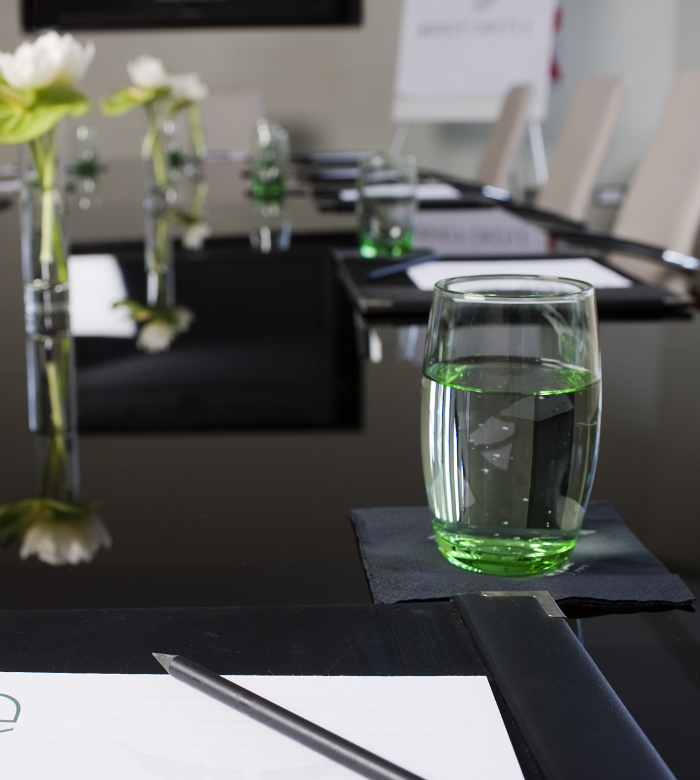 Meeting room hire with glass of water and flowers on table 
