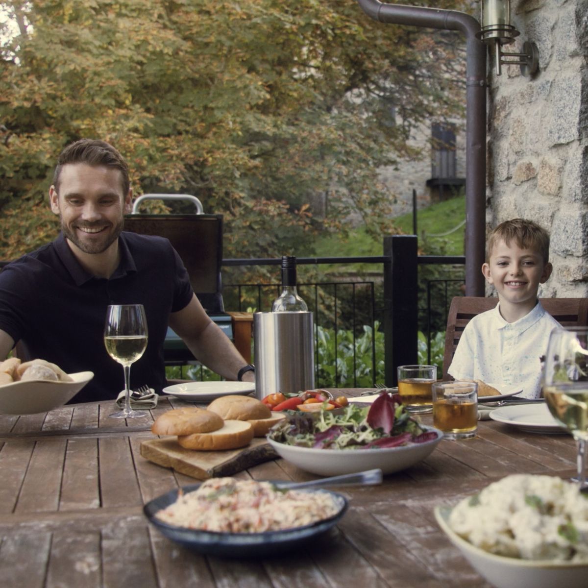 Family enjoying dinner round table outdoors smiling 