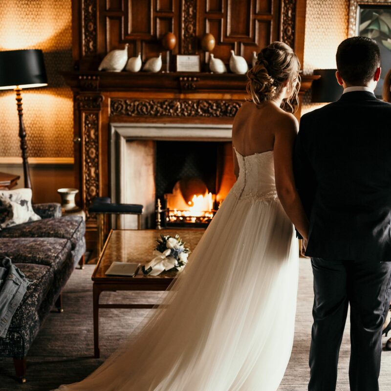 married couple holding hands in front of fireplace